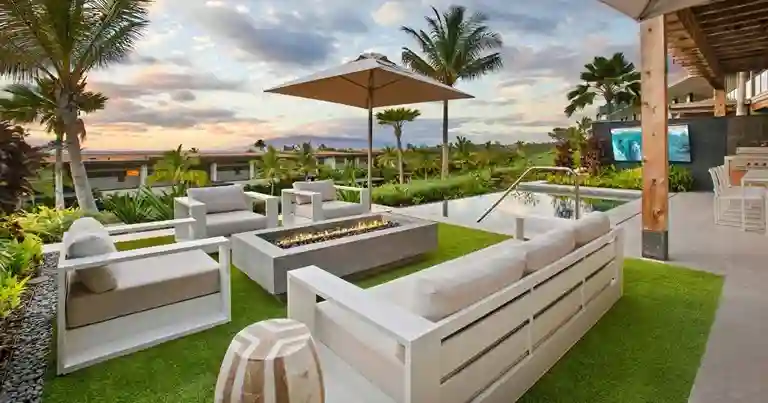 Luxe loungeset met Scandinavische tuinmeubelen rond een vuurtafel in een tropische tuin met zwembad